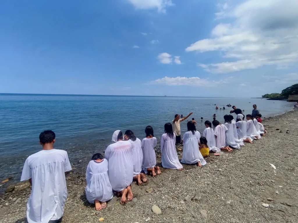 Los participantes en la iniciativa VICTORIA de La Voz de la Juventud se arrodillan en oración durante una ceremonia de bautismo a orillas del mar, que marca su compromiso con Cristo como parte de la misión del programa de llevar esperanza y salvación a las comunidades. [Foto: Ministerio Joven de la División Sudasiática del Pacífico]